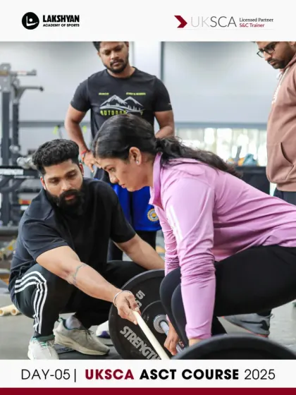 A trainer provides guidance on setting up for a deadlift, ensuring safety and optimal form during the Day 5 mock assessment session.