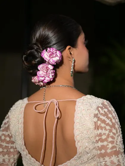 A back view of the stunning hairstyle. The sleek bun and fresh flowers create a look that is both modern and timeless.