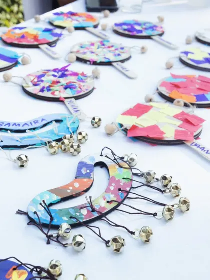 A table displaying the beautiful results of a kids' craft activity, where they painted and decorated their own tambourines and ghungroos (anklet bells).