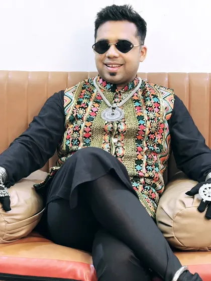 Relaxing for a moment before the show. Even when seated, the style speaks for itself with this colorful vest and traditional accessories.