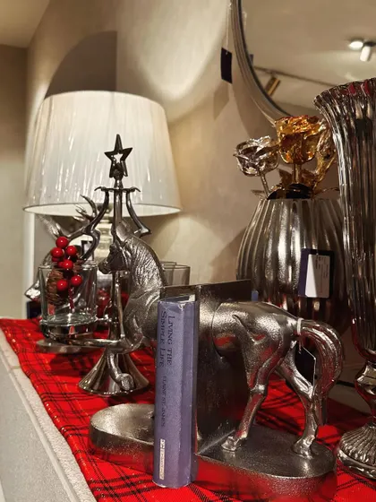 A close-up of a mantelpiece styled for Christmas, featuring our silver horse bookends and a Christmas tree-shaped accent piece.