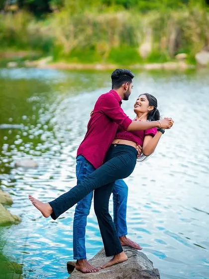 A fun and dynamic shot of the groom lifting his partner by the water's edge, full of laughter and movement.