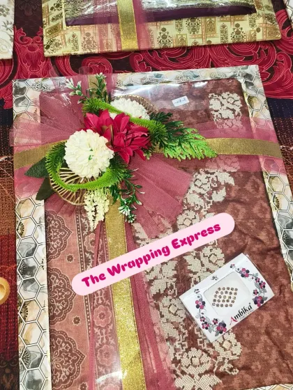 A single packed suit for a baby girl, decorated with a red flower and gold ribbon. The attention to detail makes each gift special.