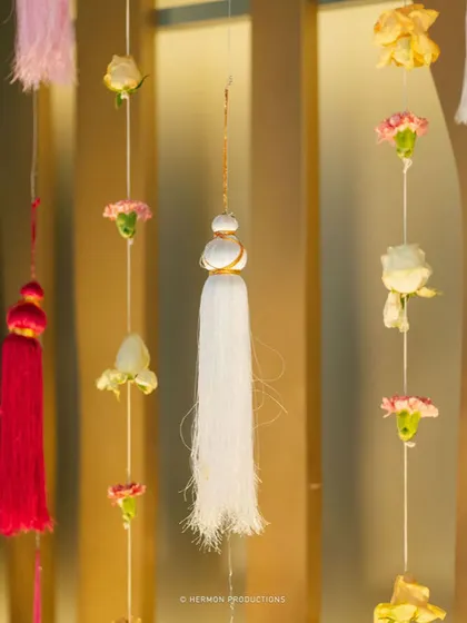 Hanging tassels and flowers as part of the Mehendi backdrop.