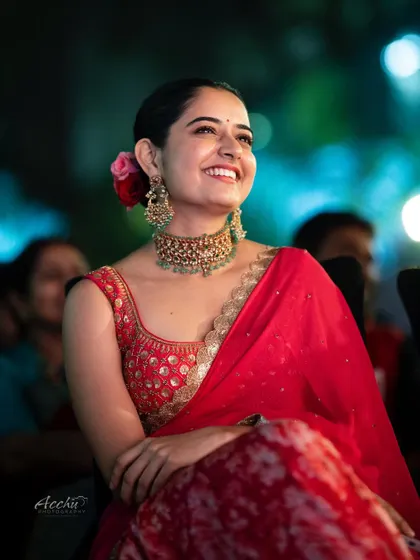 Candid moments are the best. This shot captures a genuine, joyful laugh during an event. The vibrant red saree and the festive flower in her hair make this a perfect memory from a family celebration.
