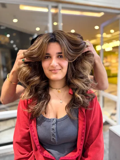A happy client showing off her voluminous, no-bleach balayage transformation.
