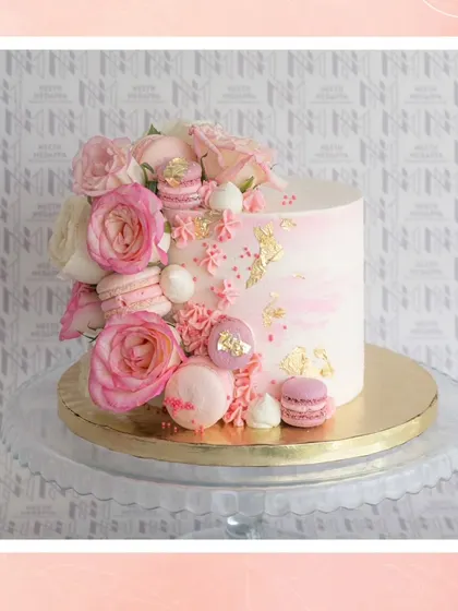 A beautiful example of a floral and macaron cake, combining soft pinks, fresh roses, and delicate meringue kisses.
