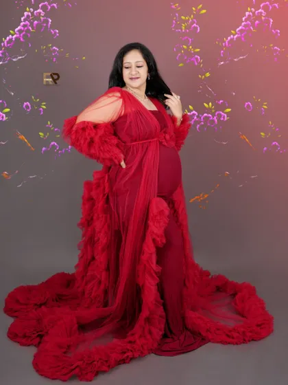 Full-length glamour. This shot showcases the entire length of the dramatic red ruffled gown against a floral-themed backdrop, creating a truly show-stopping image.