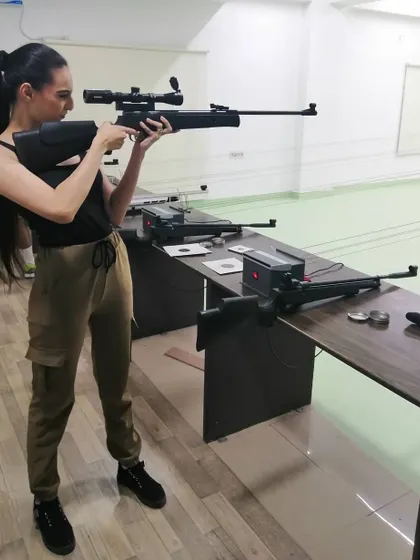 A shooter demonstrates excellent posture while aiming a scoped air rifle. Stability is key to hitting your target consistently.