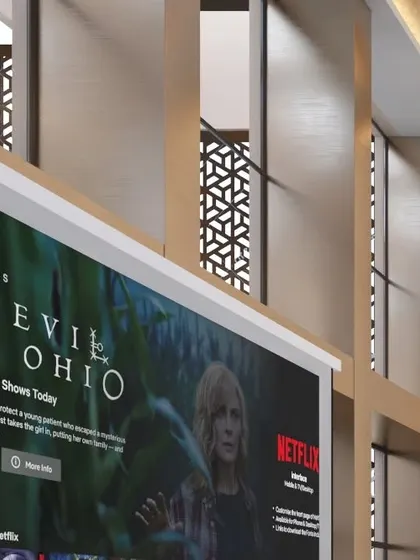 A close-up of the entertainment zone within the lounge, featuring a large projector screen for presentations or leisure. The screen is integrated into a wall with decorative laser-cut panels.