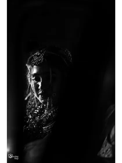 A dramatic, low-key black and white bridal portrait. The use of shadow and light creates a powerful and artistic image.