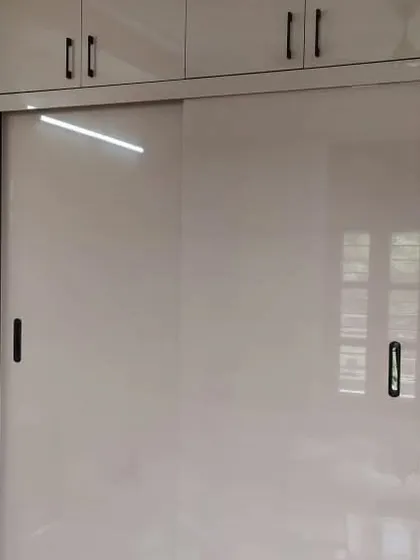 A sliding door wardrobe with a high-gloss finish, perfect for modern bedrooms where space is a premium.