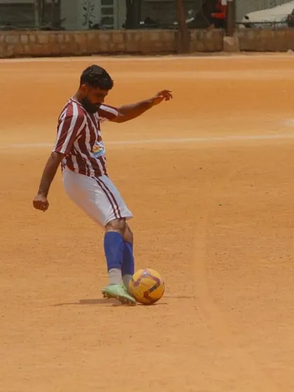 A player controls the ball on the clay pitch, demonstrating focus and technique during a competitive C-Division game.