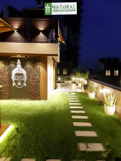 The Gwal Pahari terrace at night. The lighting design highlights the pathway, the feature wall, and the plants.