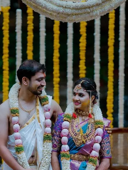 A lovely portrait of a South Indian couple during their traditional wedding ceremony, surrounded by classic floral decor.