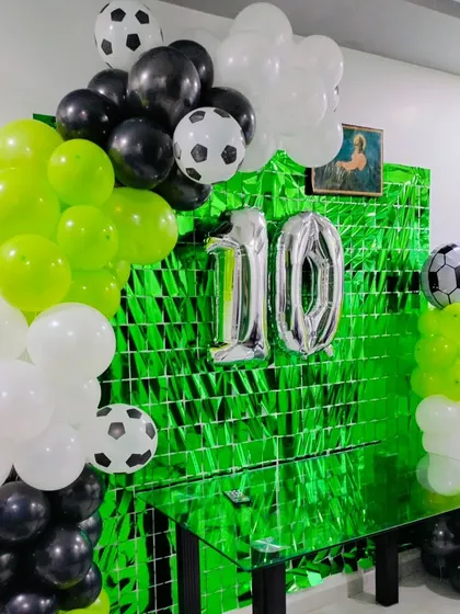A closer look at the football-themed balloon arch with black, white, and green balloons and football foil accents.