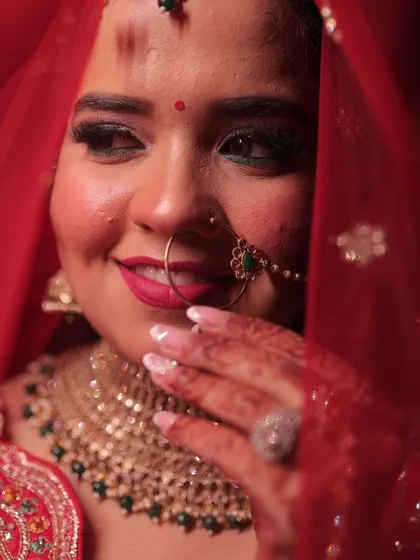 A candid, happy moment of my bride Vidushi. Her makeup is fresh and glowing, with a lovely pink lip that complements her red lehenga.