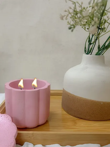 A lit pink Daisy Jar, creating a cozy and aesthetic vibe. These jars can be reused long after the candle is gone.