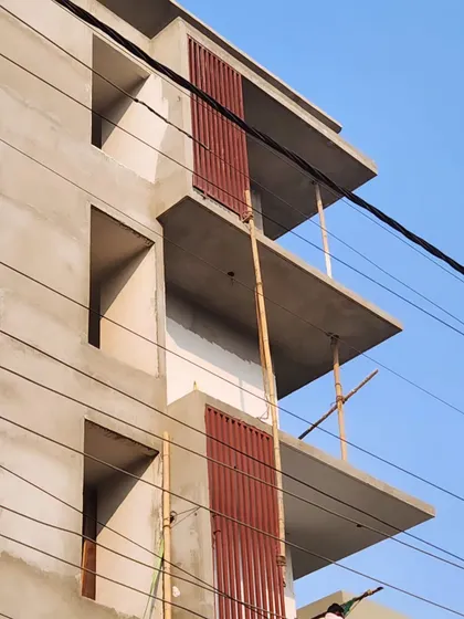 A close-up of a building's facade in progress, showing the linearity of the concrete slabs and the installation of decorative vertical fins.