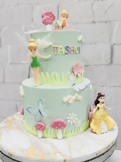 A cake fit for a little princess, featuring Tinkerbell and Belle. This two-tiered design creates a magical fairy garden scene with handcrafted mushrooms, flowers, and butterflies.
