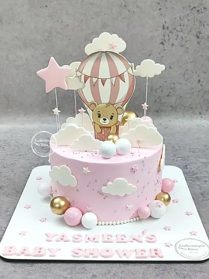 A pink hot air balloon themed cake for Yasmeen's baby shower. This adorable cake features a teddy bear, clouds, and stars.