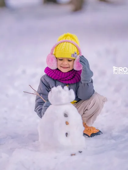 A proud moment for my daughter with the snowman she built. Capturing children's creativity and joy is one of my favorite parts of family photography.