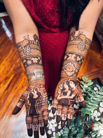 A full view of a custom baby shower mehendi with a dark, rich stain. The design combines couple portraits with traditional Indian architectural and peacock motifs.
