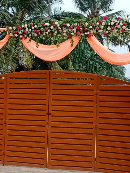 A simple yet elegant entrance gate decorated with peach drapes and a floral garland.