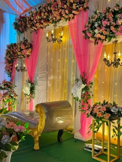 An angled view of the pink and gold engagement stage, showing the depth and richness of the floral arrangements.