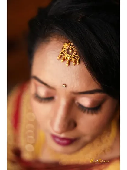 A high-angle close-up of the bride, focusing on her serene expression and traditional forehead jewelry.