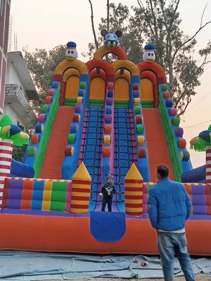 Here is our 4-lane colorful bouncy slide set up outdoors. You can see how tall and impressive it is, with people standing next to it for scale.