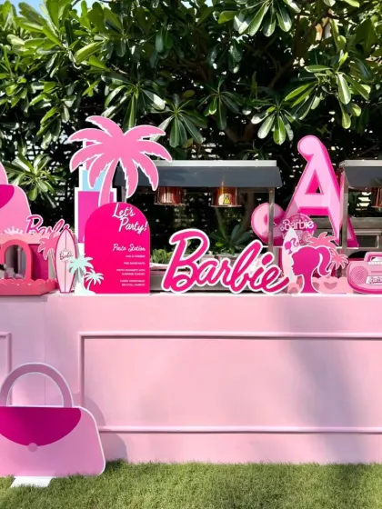 The main food station, adorned with Barbie logos, palm trees, and other fun cutouts, creating a fantastic visual centerpiece for the party.