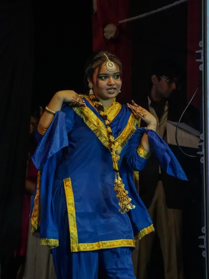 A student in a traditional blue and gold Punjabi suit performs a folk dance at Memorabilia.