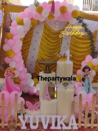 An outdoor princess party setup. The pink, white, and gold balloon arch looks beautiful against the tent backdrop.