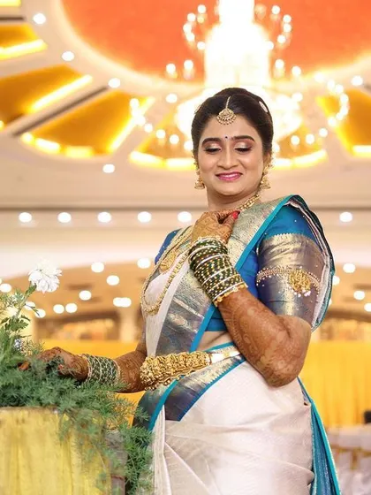 Hamsa looking picture perfect for her muhurtham. The makeup is elegant and timeless, with a focus on enhancing her natural features to match the grandeur of the wedding hall.
