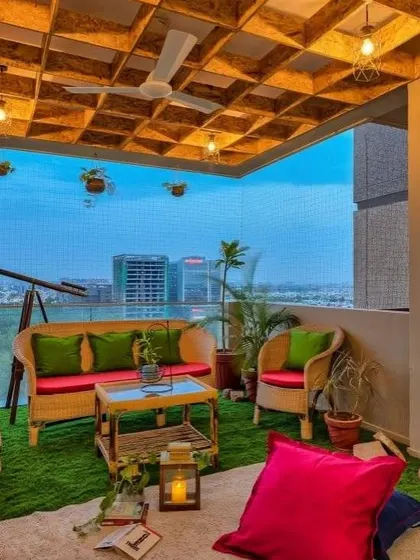 This spacious balcony is designed for evening gatherings, featuring a cane sofa set with bright cushions. The safety net ensures security without obstructing the view, and the unique ceiling adds architectural interest.
