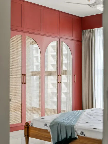 A peek into the master bedroom, showing the beautiful arched cane and glass wardrobe doors against the rich burgundy color.