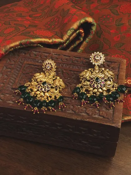 A pair of stunning temple jhumkas with peacock motifs and green bead drops. These can be rented separately to match any traditional outfit.
