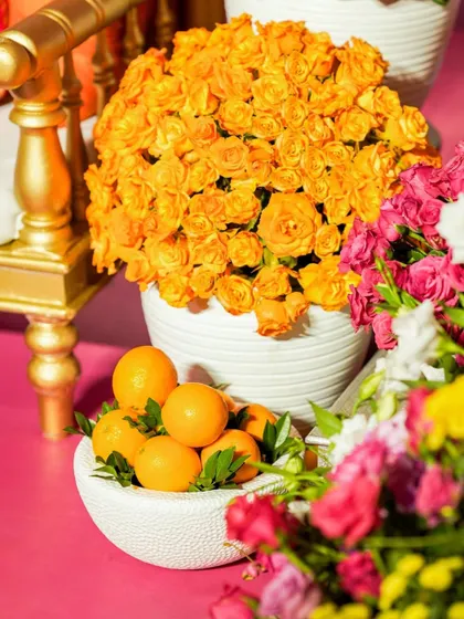 A detail shot combining a bowl of fresh oranges with a vibrant bouquet of orange spray roses, highlighting our use of natural elements in the decor.