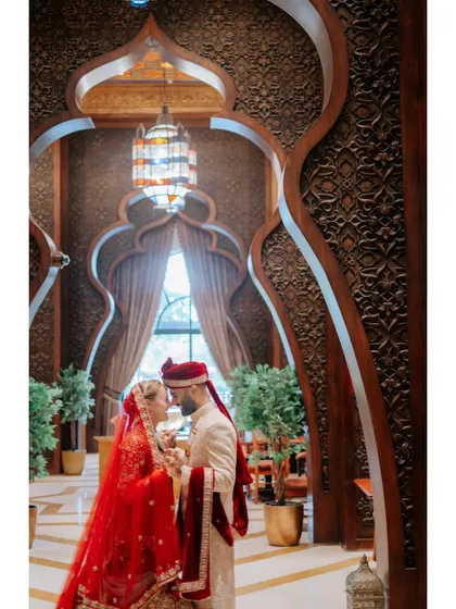 A grand and intimate portrait of the couple inside a beautifully designed Dubai venue, showcasing the stunning architecture and their regal wedding attire.