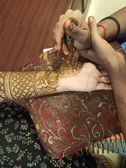 My team and I always ensure the client is comfortable during the mehndi application. Here, an artist carefully works on a detailed forearm piece.