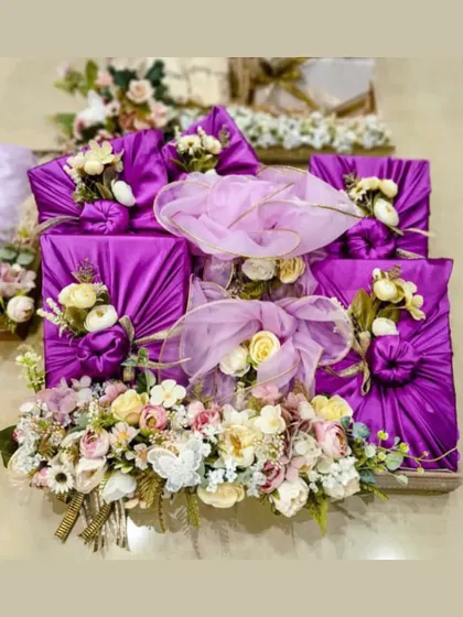 This is what we mean by luxury gifting. For this wedding trousseau, we wrapped each gift in rich purple satin fabric, decorated with floral arrangements, and presented them on an elegant wooden tray.