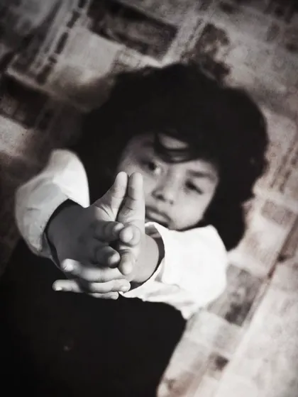 A creative and artistic shot, focusing on the boy's hands as he makes a playful gesture towards the camera.