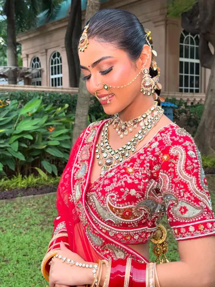 A glimpse of a beautifully accessorized braid on a traditional bride. The hairstyle is designed to complement her intricate jewelry and red lehenga.