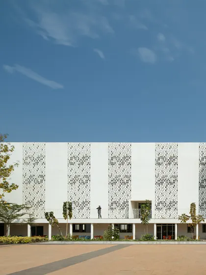 The facade of Vidyashilp Academy is a study in material intelligence. The large 'jaali'-inspired panels are not just decorative; they filter sunlight, maintain privacy, and ensure constant airflow, elevating simple materials into purposeful elements of climate-responsive design.