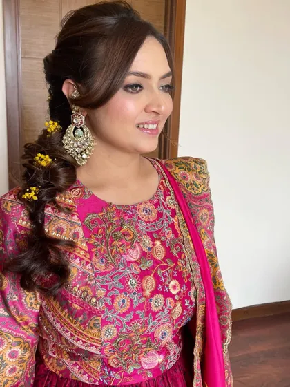 A side profile showing the intricate messy braid with floral details, paired with glowing makeup for a Mehendi.