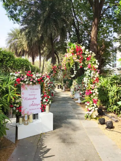 A beautiful floral pathway for an outdoor wedding, with lush arches of red, pink, and white flowers guiding guests to the ceremony.