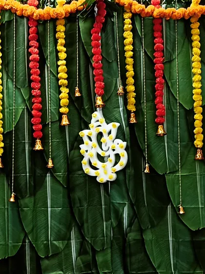 Here is a purely traditional backdrop I created using a base of fresh banana leaves. The vibrant contrast of yellow and red marigold garlands, along with a central Ganesha motif and hanging bells, makes it perfect for an auspicious pooja.