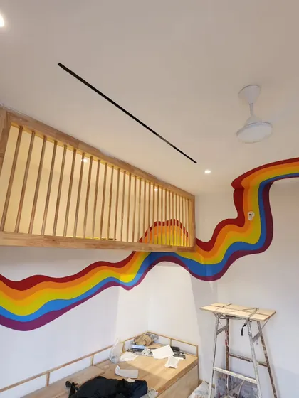 The rainbow mural as it curves around the loft structure, creating a continuous band of color.