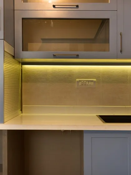A close-up of the utility area in the blue kitchen, showcasing the thoughtful storage solutions, under-cabinet lighting, and a sleek black sink.